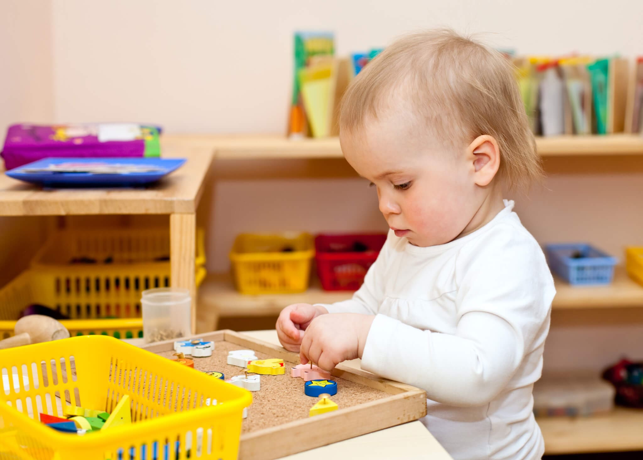 Child at nursery. Little baby girl playing with wooden toys at nursery