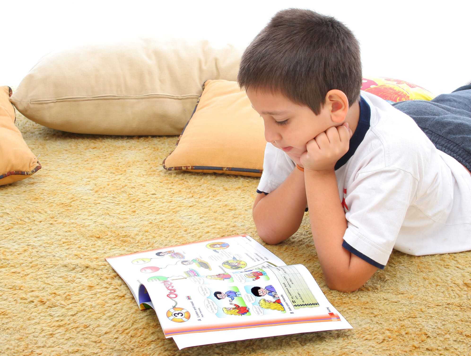Boy reading a book on the floor. Boy in a room reading a book over a carpet. He looks interested and concentrated. Visit my gallery for more images of children